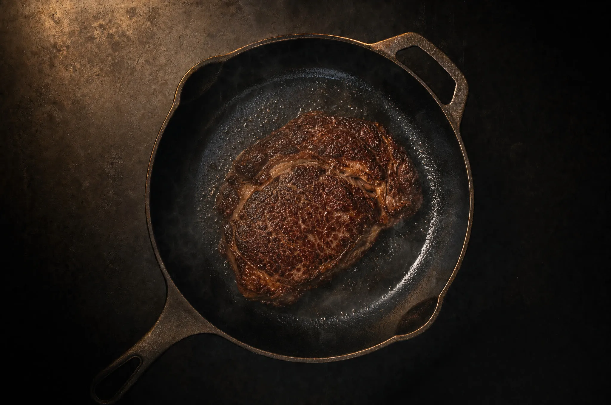 Thick ribeye searing in a hot cast iron skillet with a deep brown crust and wisps of smoke